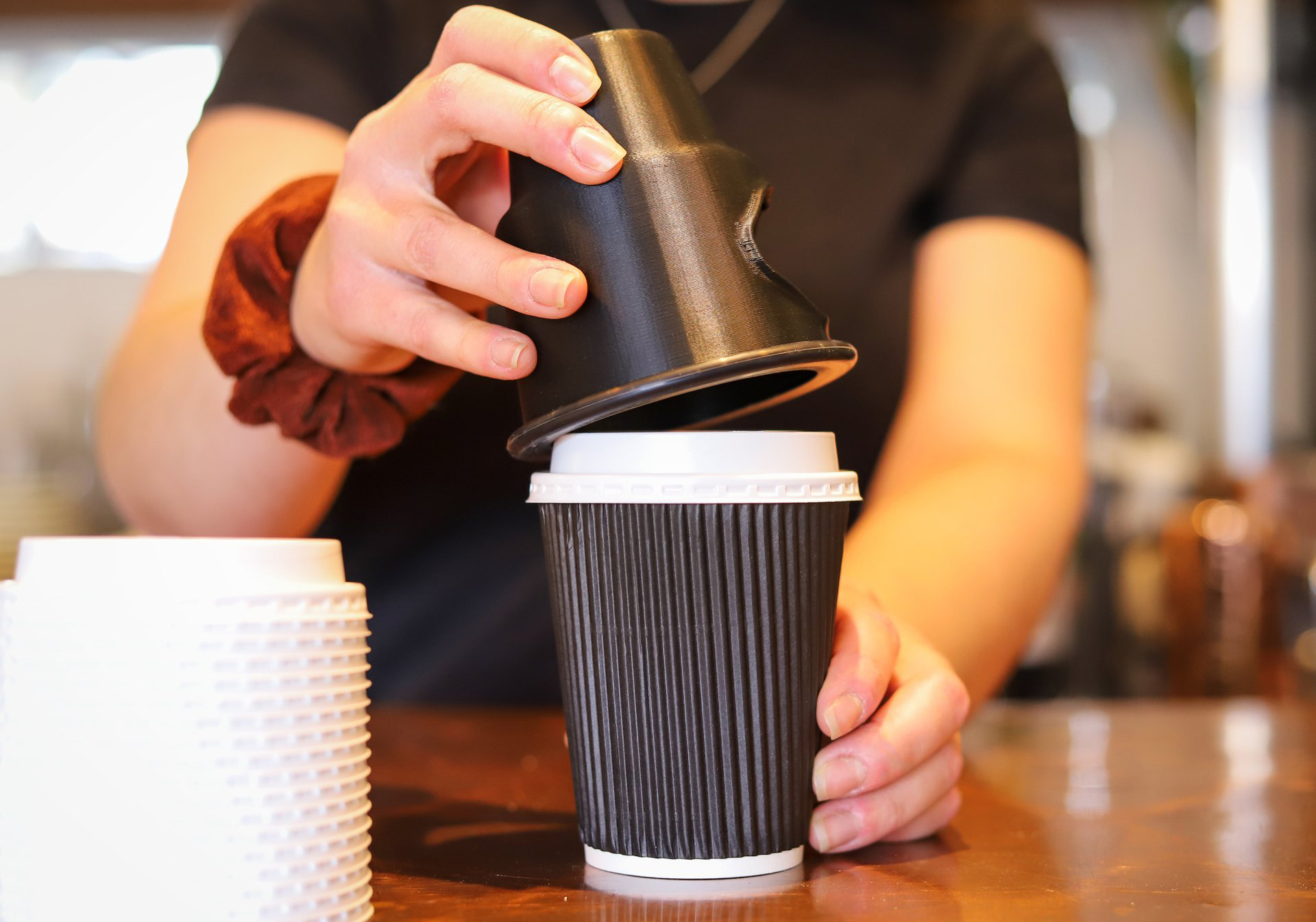 employee using lid safe to apply lid to coffee cup